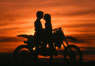 Photo of couple with motorcycle in silhouette at sunset